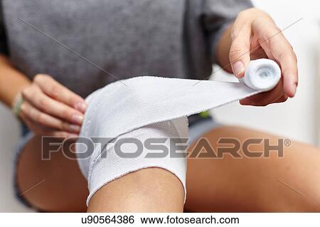 Woman wrapping bandage around knee View Large Photo Image Stock Photograph - Woman wrapping bandage around knee. Fotosearch