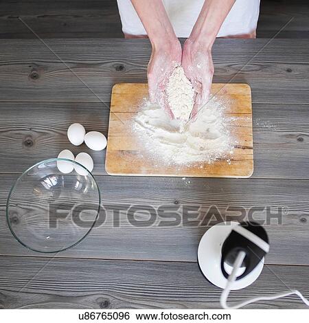 Stock Photograph - Woman's hands holding flour at kitchen table. Fotosearch