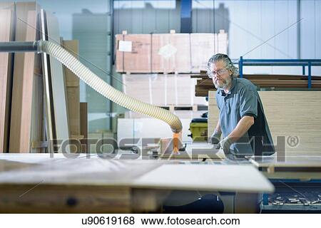 Stock Photo - Worker cutting timber in motorhome factory. Fotosearch