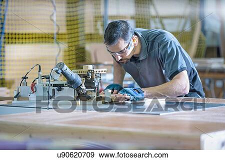 Stock Photo - Worker cutting timber in motorhome factory. Fotosearch