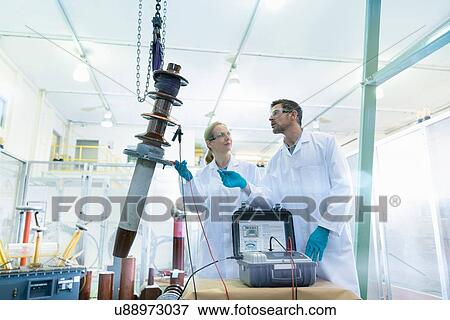 Stock Photo - Workers inspecting electrical insulator from power distribution network. Fotosearch