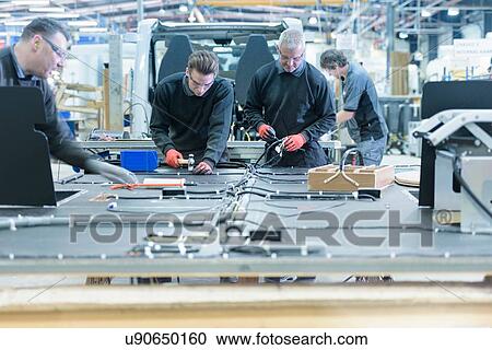 Stock Image - Workers on motorhome production line. Fotosearch