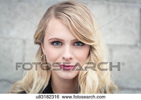 Young blonde haired woman in front of breeze block wall looking at camera smiling View Large Photo Image Stock Photograph - Young blonde haired woman in front of breeze block wall looking at camera smiling. Fotosearch