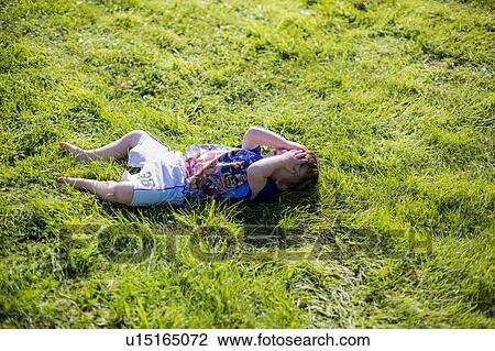 Young boy lying on grass View Large Photo Image Stock Image - Young boy lying on grass. Fotosearch