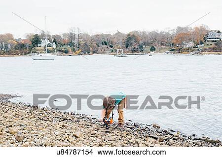 Young boy picking up stones beside lake View Large Photo Image Picture - Young boy picking up stones beside lake. Fotosearch