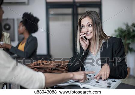 Stock Photo - Young businesswoman making query at office reception. Fotosearch