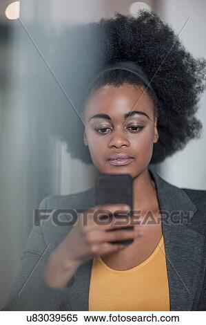 Stock Photography - Young businesswomen reading smartphone text at office. Fotosearch