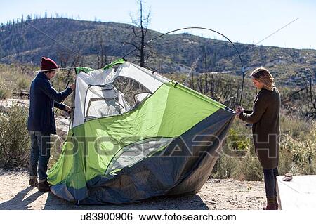 Stock Photograph - Young couple erecting tent in rural setting. Fotosearch
