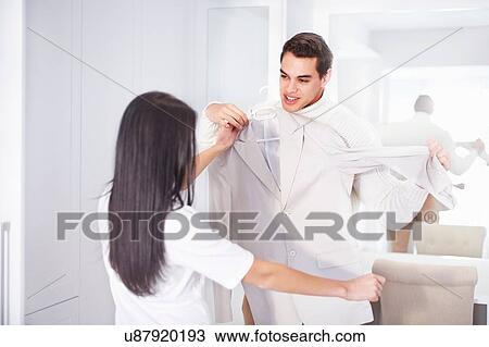 Stock Image - Young couple getting ready together in bedroom. Fotosearch