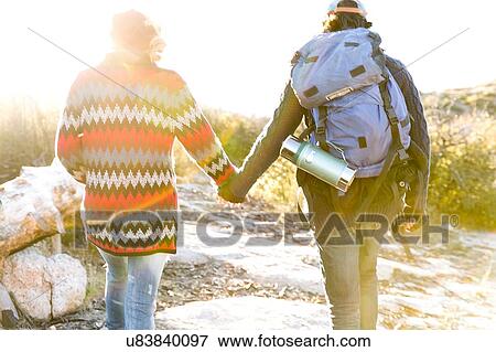 "Young couple hiking in rural setting, holding hands, rear view" View Large Photo Image Stock Photo - "Young couple hiking in rural setting, holding hands, rear view". Fotosearch