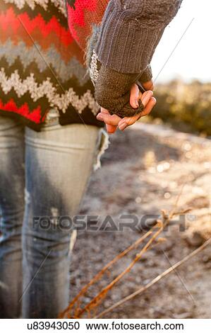 Stock Image - "Young couple holding hands, mid section". Fotosearch