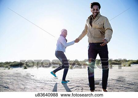 Young couple holding hands on beach in winter View Large Photo Image Stock Photo - Young couple holding hands on beach in winter. Fotosearch