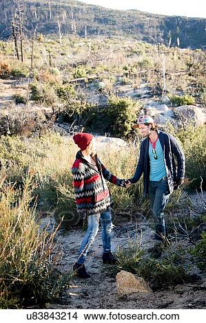 Picture - "Young couple in rural setting, walking, holding hands". Fotosearch