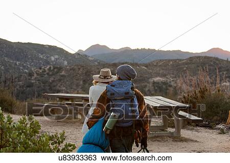 Stock Image - "Young couple in rural setting, carrying camping equipment". Fotosearch