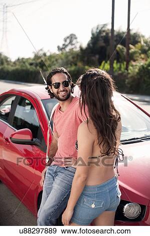 Young couple leaning against red car at roadside, Los Angeles, California, USA View Large Photo Image Stock Photo - Young couple leaning against red car at roadside, Los Angeles, California, USA. Fotosearch