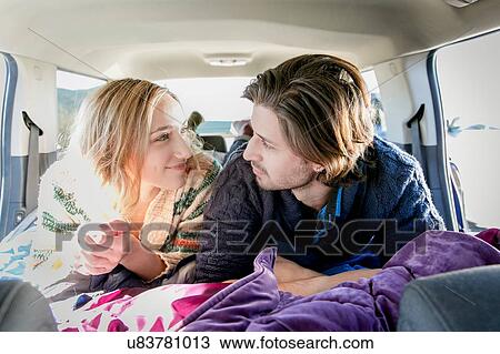 Stock Image - "Young couple lying down in recreational vehicle, smiling". Fotosearch