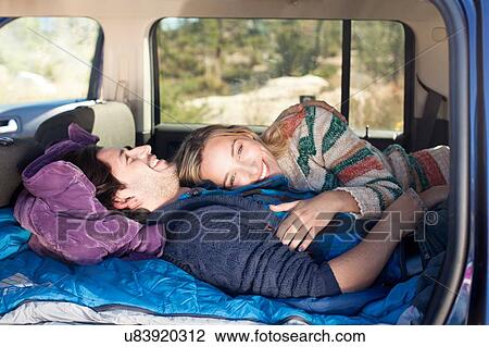 Stock Image - "Young couple lying down in recreational vehicle, smiling". Fotosearch