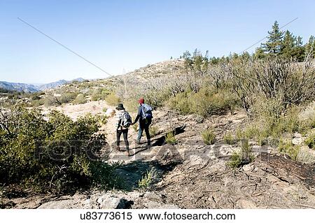 Stock Photography - "Young couple outdoors, hiking, holding hands, rear view". Fotosearch