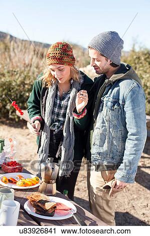 "Young couple preparing food, standing beside picnic table in rural setting" View Large Photo Image Stock Image - "Young couple preparing food, standing beside picnic table in rural setting". Fotosearch