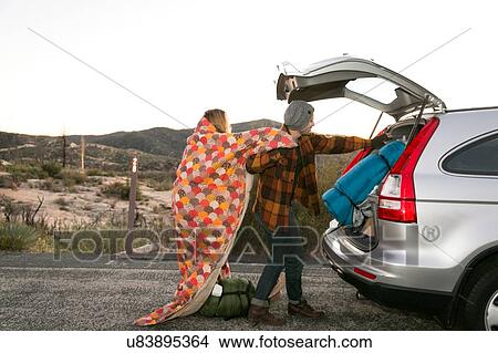 Young couple putting camping equipment in boot of car View Large Photo Image Picture - Young couple putting camping equipment in boot of car. Fotosearch