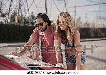 Young couple reading roadmap on car bonnet, Los Angeles, California, USA View Large Photo Image Stock Photo - Young couple reading roadmap on car bonnet, Los Angeles, California, USA. Fotosearch