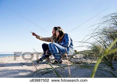 "Young couple relaxing on beach, looking at view" View Large Photo Image Stock Image - "Young couple relaxing on beach, looking at view". Fotosearch