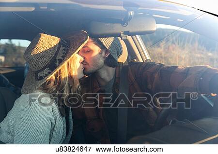 Stock Photo - "Young couple sitting in car, kissing, seen through car windscreen". Fotosearch