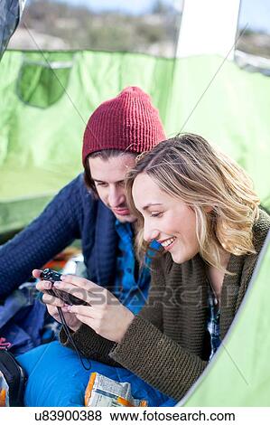 "Young couple sitting in tent, looking at photographs on camera" View Large Photo Image Stock Photo - "Young couple sitting in tent, looking at photographs on camera". Fotosearch