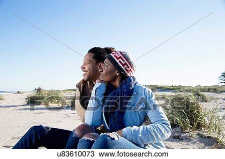 "Young couple sitting on beach, looking at view" View Large Photo Image Stock Image - "Young couple sitting on beach, looking at view". Fotosearch