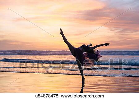 Stock Photography - "Young female dancer wearing chiffon dress, dancing on beach at sunset, San Diego, California, USA". Fotosearch