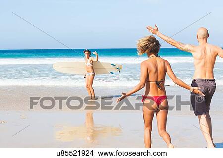 Picture - Young female surfer waving to friends on beach, El Cotillo, Fuerteventura, Spain. Fotosearch