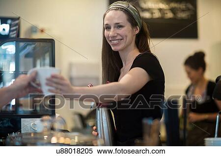 Stock Photography - Young female waitress handing cup of coffee to cafe customer. Fotosearch