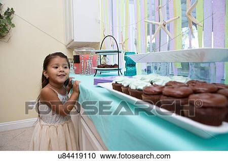 Young girl looking longingly at cakes on kitchen work surface View Large Photo Image Stock Image - Young girl looking longingly at cakes on kitchen work surface. Fotosearch