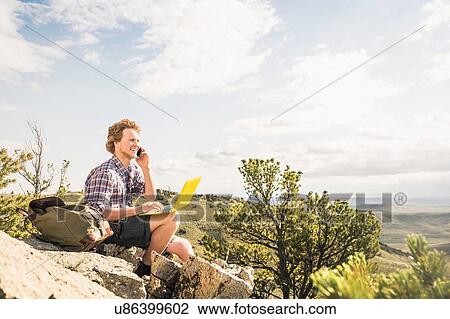 Young male hiker sitting on rocks talking on smartphone, Bridger, Montana, USA View Large Photo Image Stock Image - Young male hiker sitting on rocks talking on smartphone, Bridger, Montana, USA. Fotosearch