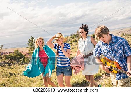 Young man and female friends playing ukulele and walking in hills, Bridger, Montana, USA View Large Photo Image Stock Image - Young man and female friends playing ukulele and walking in hills, Bridger, Montana, USA. Fotosearch