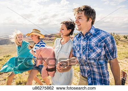 Stock Image - Young man and female friends walking in hills, Bridger, Montana, USA. Fotosearch