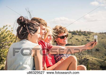 Young man and friends taking smartphone selfie in hills, Bridger, Montana, USA View Large Photo Image Stock Photo - Young man and friends taking smartphone selfie in hills, Bridger, Montana, USA. Fotosearch