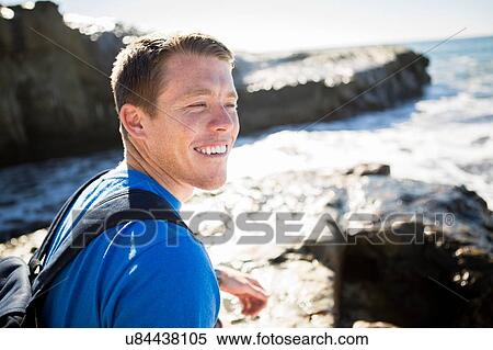 Stock Photography - "Young man beside sea, smiling". Fotosearch