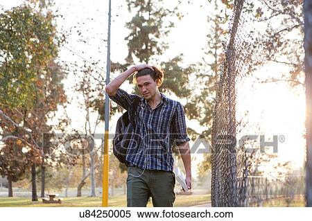 "Young man carrying backpack and book, hand in hair" View Large Photo Image Stock Photography - "Young man carrying backpack and book, hand in hair". Fotosearch