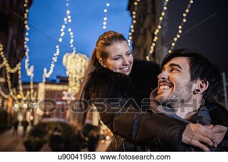 Stock Image - Young man giving young woman piggyback face to face smiling. Fotosearch