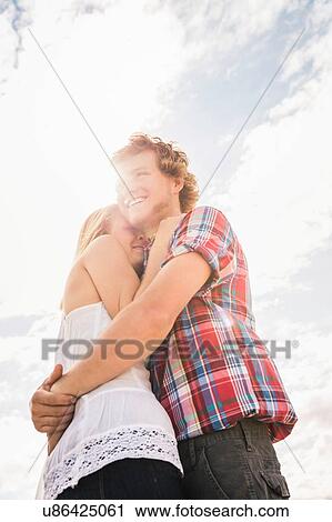 Young man hugging girlfriend against sunlit sky View Large Photo Image Stock Image - Young man hugging girlfriend against sunlit sky. Fotosearch