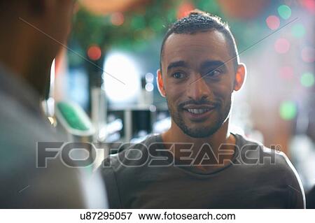 Stock Photo - Young man in public house looking away smiling. Fotosearch
