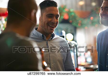 Young man in public house with friends smiling View Large Photo Image Stock Photography - Young man in public house with friends smiling. Fotosearch