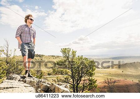 Young man looking out from rocks at landscape, Bridger, Montana, USA View Large Photo Image Stock Image - Young man looking out from rocks at landscape, Bridger, Montana, USA. Fotosearch