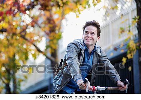 Stock Photography - Young man looking sideways whilst cycling. Fotosearch