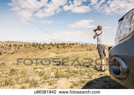Stock Image - Young man photographing landscape, Bridger, Montana, USA. Fotosearch