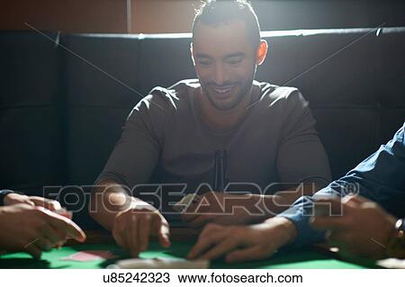 Young man picking up card game winnings at pub card table View Large Photo Image Stock Image - Young man picking up card game winnings at pub card table. Fotosearch
