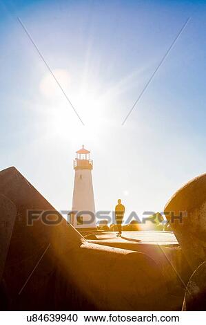 Stock Image - Young man skating on skateboard near lighthouse. Fotosearch