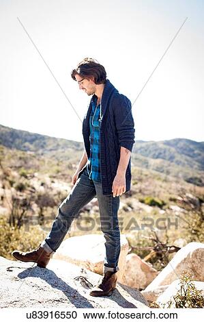Stock Image - "Young man, standing on rocks in rural setting". Fotosearch