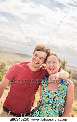 Stock Image - Young man with arm around girlfriend in hills, Bridger, Montana, USA. Fotosearch